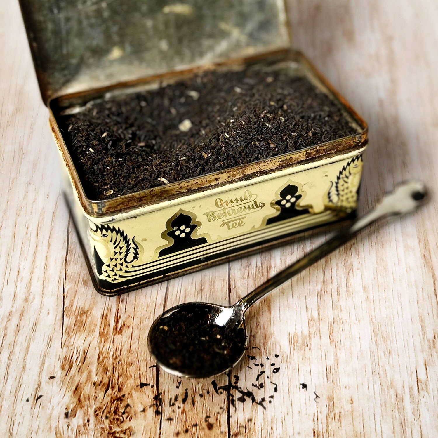 Geöffnete Metalldose mit der Aufschrift Onno Behrends Tee. Gefüllt mit losem Schwarztee, davor ein Teelöffel